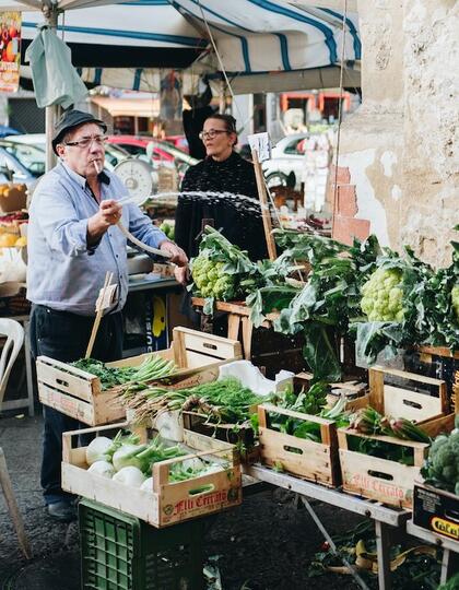 A vendor washes vegetables at a Palermo food market