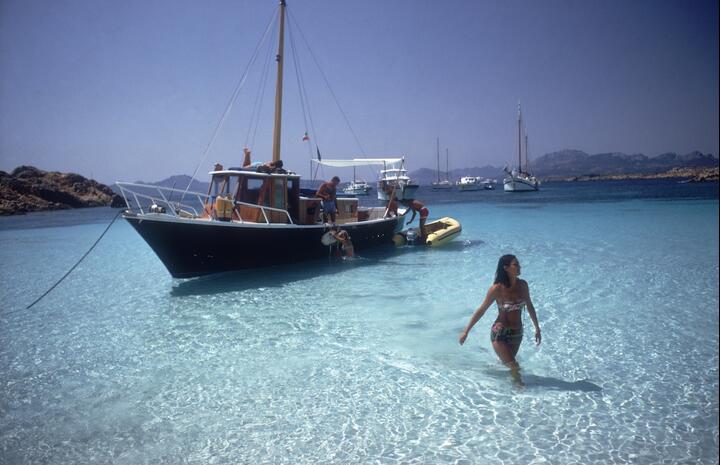 Wading through the transparent waters of Costa Smeralda, photographed by Slim Aarons, 1967.