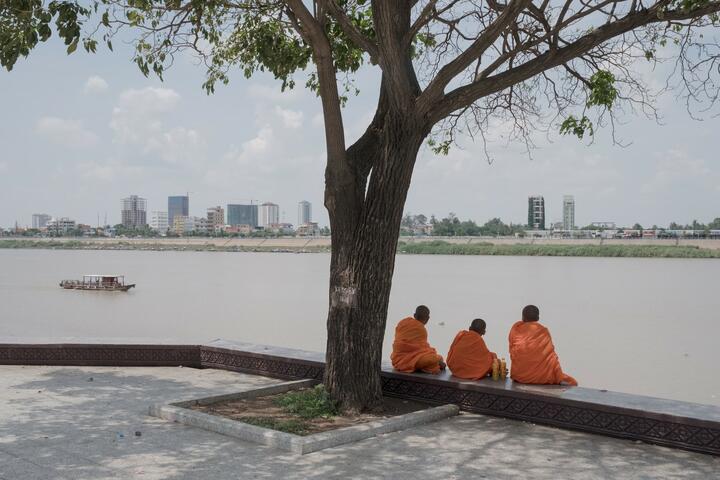 Three buddhist monks hang out on the riverside in Phnom Penh.