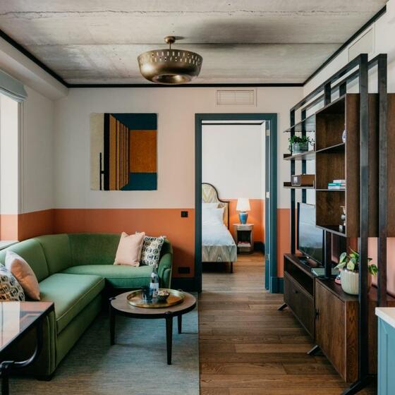 A colourful aparthotel bedroom with wood floors and raw concrete ceiling