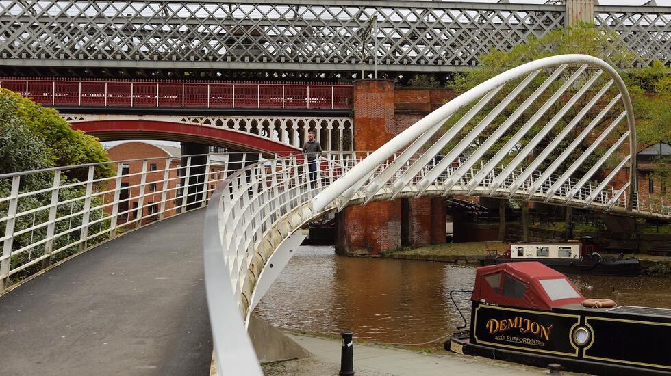 A man walks over a canal bridge in Ancoats