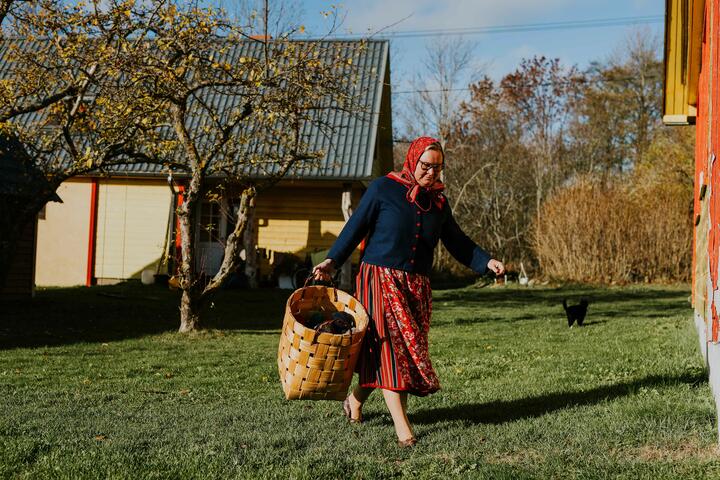 A woman in a traditional skirt crosses a grassy backyad