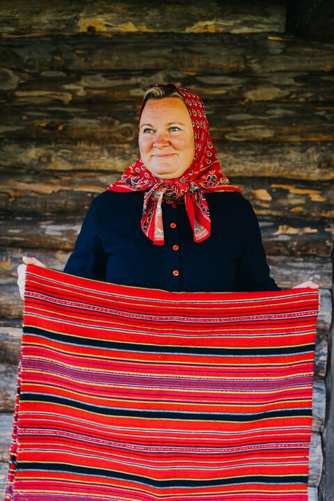 A woman holds up a bright red stretch of woven fabric