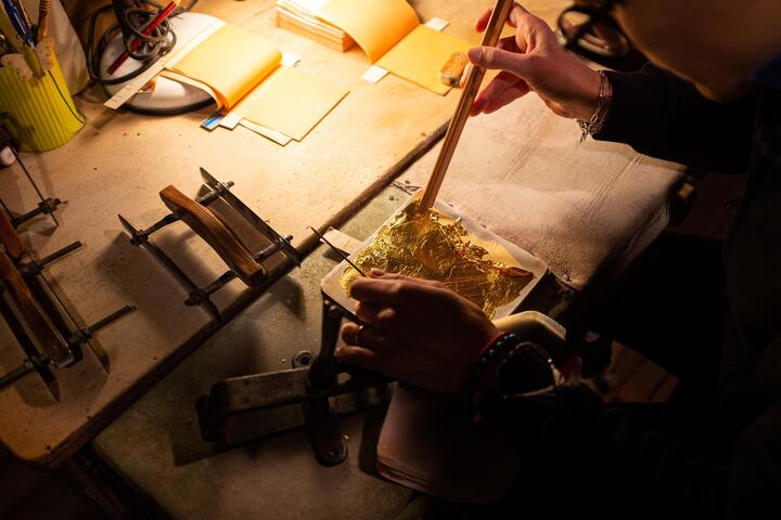 A craftsperson works with gold leaf in venice