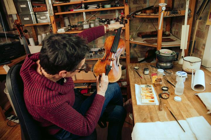 A woman holds up the body of a violin