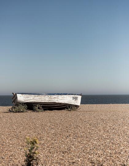 A boat lies on its side on the shingle