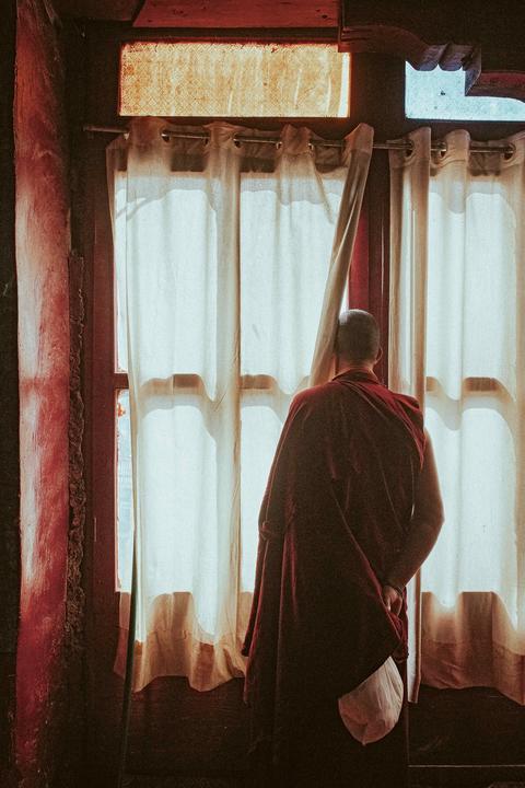 A monk peeking out a window in Ladakh