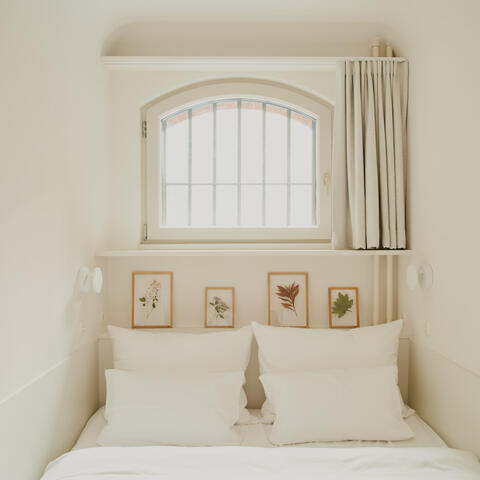 A whitewashed bedroom housed in a transformed cell at Wilmina Hotel, Berlin