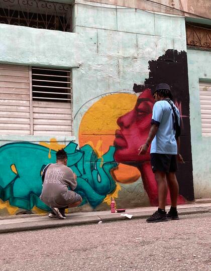 Two artists work on a colourful mural