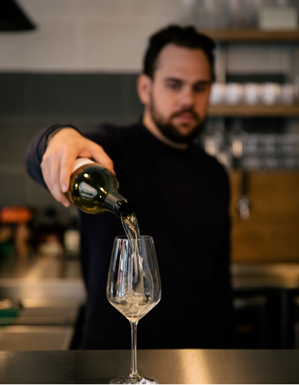 Sommelier Will Sutton pours wine into a glass